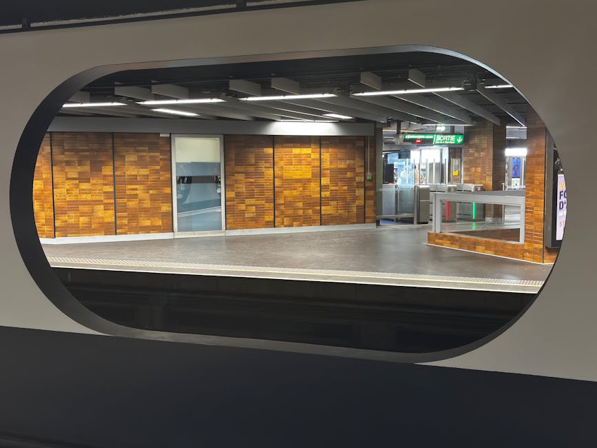 An empty interior carriage of Gunnersbury Station with a clean, tiled floor and well-maintained seating areas. The floor appears polished and dust-free, with patterned fabric seats arranged along the
